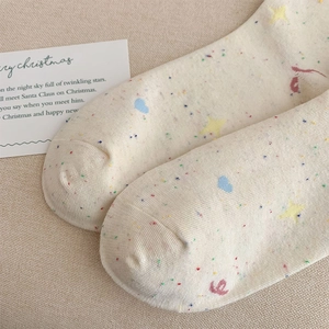 Close-up of beige cotton socks featuring colorful dots, blue hearts and yellow star patterns
