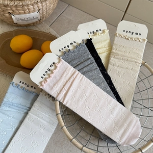 Dettaglio di calze con bordo a balze e motivo jacquard a farfalla in vari colori