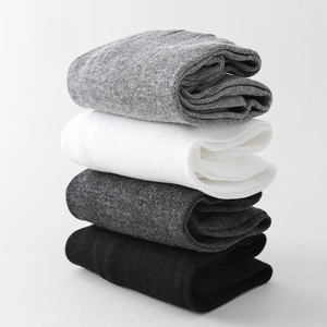 Close-up of four-color stacked minimalist calf socks in grey, white, and black tones