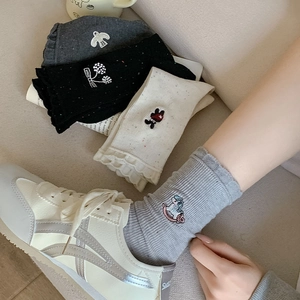 Detailed view of women's ribbed crew socks with cute cartoon embroidery and frilled cuffs