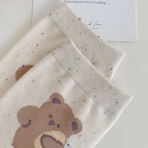 Detailed texture of cotton knit socks featuring colorful polka dots and cute bear patterns