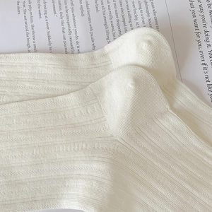 Macro shot of vertical rib knit texture on soft off-white cotton blend socks