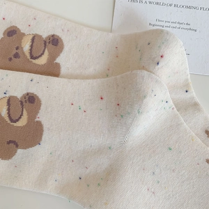 Detailed knit texture of beige crew socks with colorful speckles and cute bear pattern