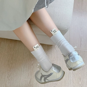 Gros plan de chaussettes blanches à côtes avec étiquette coeur et baskets rétro