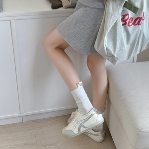 Détail de chaussettes montantes côtelées beige clair avec étiquette et baskets rétro