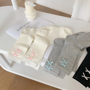 Detailed close-up of ribbed knit socks with delicate silk ribbon bow accents on the cuffs
