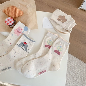 Detail of oatmeal speckled socks with cartoon bear patterns and wavy ruffle cuffs
