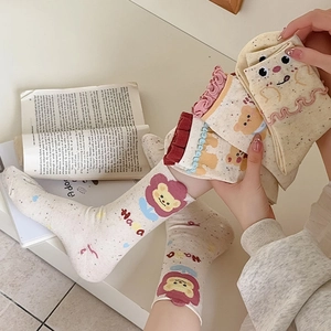 Close-up of cute cotton socks with lettuce trim and cartoon bear patterns on a cream base