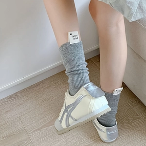 Gros plan de chaussettes en maille grise côtelée avec des baskets blanches rétro au sol