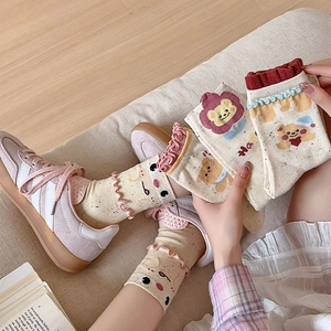 Detailed close-up of cream knit mid-tube socks with cute bear and floral embroidery