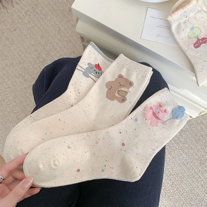 Detailed knit texture of mid-calf socks featuring cute cartoon bear and dog patterns