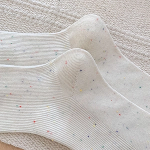 Close-up of white rib-knit cotton socks with colorful rainbow speckles and soft texture
