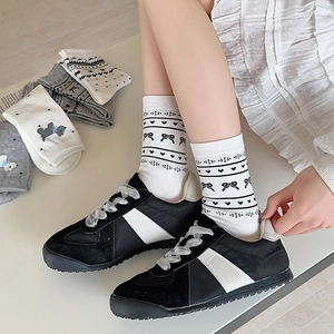 Close-up of white crew socks with black bows and heart patterns for a college style