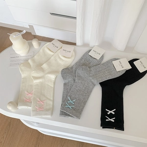 Detail of ribbon bows and vertical knit textures on three pairs of stylish cotton socks