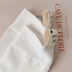 Gros plan détaillé sur des chaussettes blanches côtelées avec étiquette cœur minimaliste