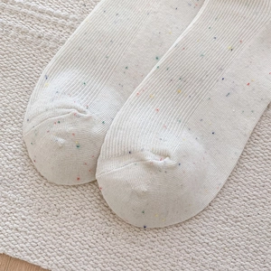 Close-up of white knitted socks with colorful speckles and fine ribbed texture