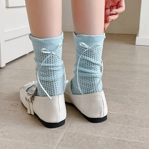 Détail de chaussettes bleues en maille ajourée avec nœud en ruban et texture résille