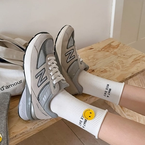 Close-up of grey mesh sneakers with N logo and cute rainbow smiley face letter socks