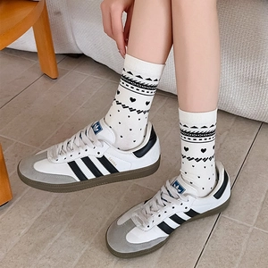 Detailed knit texture of cream mid-calf socks with black heart patterns and ribbed cuffs