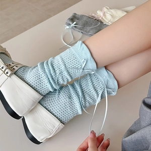 Gros plan de chaussettes en maille ajourée bleu clair avec nœud en ruban de soie