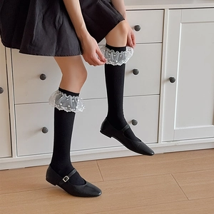 Détail de chaussettes hautes noires avec dentelle blanche et pois style JK