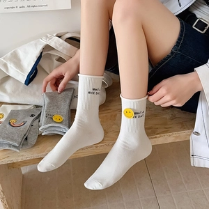 Detail of cotton socks with yellow smiley face patches and 'WHAT A NICE DAY' embroidery