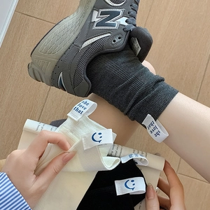 Detail of ribbed knit crew socks with 'she love that' smiley face patch on ankle