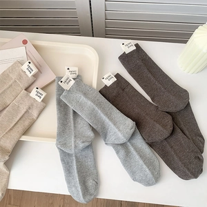 Vue détaillée de chaussettes en coton neutre avec texture côtelée et étiquette décorative