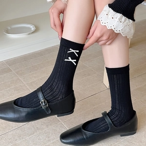 Close-up of black ribbed crew socks with white bow embroidery paired with Mary Jane shoes