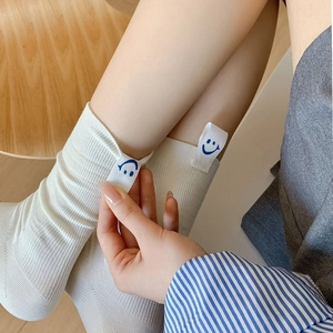 Close-up of white ribbed knit socks featuring a blue smiley face label on the side
