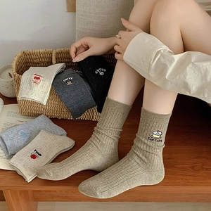Detail of cotton crew socks featuring cute cartoon embroidery and ribbed knit texture
