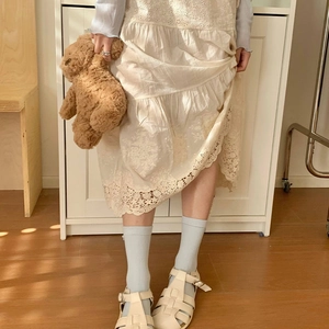 Dettaglio calzini blu in maglia con bottoni a conchiglia e bordo abito in pizzo beige