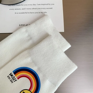 Detailed close-up of ribbed cuffs on white cotton socks with rainbow embroidery