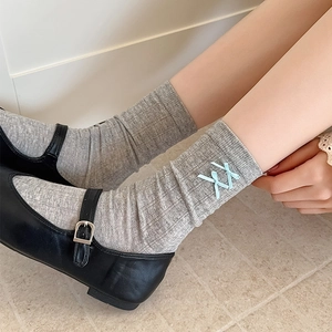 Detail of grey ballet-style socks with light blue bows paired with black Mary Jane shoes