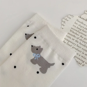 Detail of white cotton sock featuring a cute grey puppy pattern with black polka dots