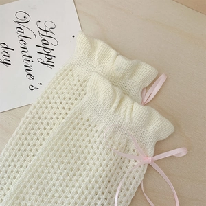 Détail des chaussettes en maille crème avec de jolis nœuds en ruban rose pastel