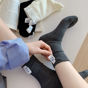 Detail of ribbed cotton mid-calf socks with letter fabric label and blue smiley face icon