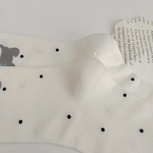 Detail shot of white polka dot crew socks with cute bear embroidery on cotton fabric