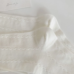 Close-up of white knitted socks featuring wave textures and breathable hollow details