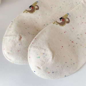 Detailed close-up of cream knit socks with colorful speckles and cute cartoon koala print