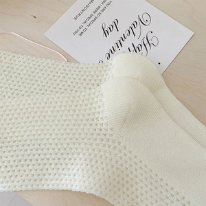 Vue détaillée de la texture en maille ajourée respirante sur des chaussettes mi-mollet blanc cassé
