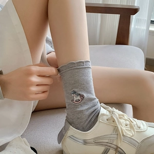 Detail of light gray ribbed socks with colorful unicorn embroidery and wavy ruffled edge