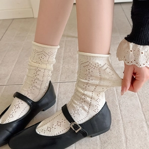 Detail of cream hollow knit crew socks with mesh patterns and rolled cuffs