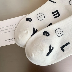Detailed close-up of white knitted socks featuring black alphabet and smiley face print