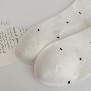 Close-up of white polka dot cotton socks with focus on neat toe stitching and soft texture