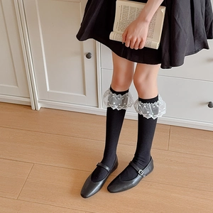 Détail de chaussettes noires en tricot côtelé avec bords à volants en dentelle blanche