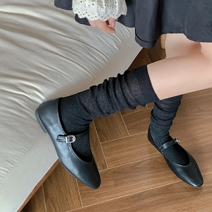 Classic black Mary Jane shoes with glittery socks on a warm wooden floor background