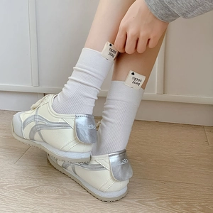 Détail de chaussettes blanches côtelées avec étiquette cœur et baskets à accents argentés