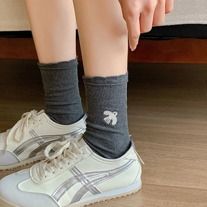 Detail of dark grey ribbed socks featuring cute bird embroidery with casual sneakers