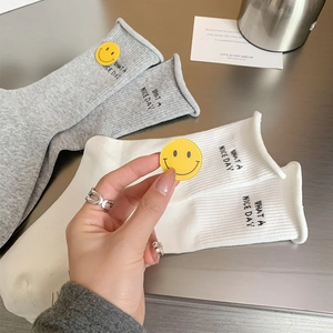 Close-up of cotton knit socks featuring 'WHAT A NICE DAY' embroidery and yellow smiley badges